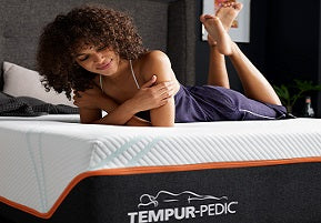 Woman laying on a Tempur-pedic mattress smiling