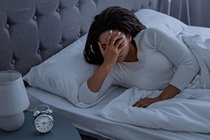 A woman holding her head in bed