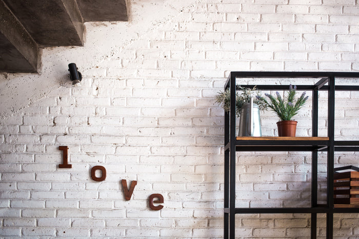 bookcase on a brick wall with the word love spelled out on the wall