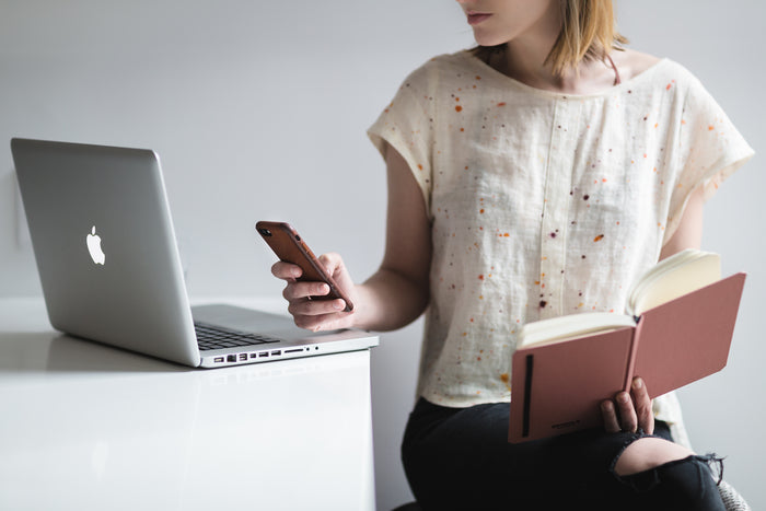 person with a book, cellphone, and laptop